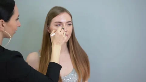 Make-up artist applying foundation on the face of a woman by brush. Salon Stock Footage 154964899