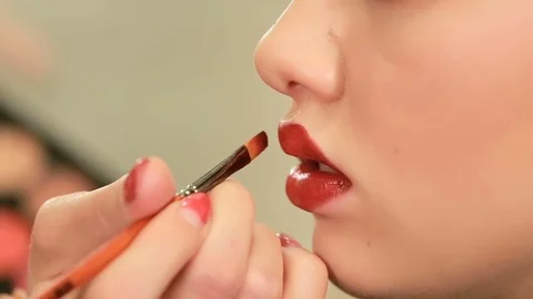Make up artist applying lipstick with brush on pretty gorgeous woman lips Stock Footage 74691062