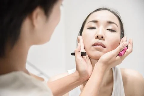 Make up artist applying make up to clean face a fashion model or bride Stock Photos