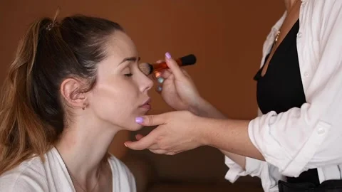 Make-up artist applying makeup to a young model in a makeup studio with a bru Video stock 134561672