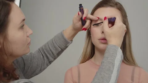 Make-up artist in beauty studio doing makeup for beautiful girl. Woman making Stock Footage 154892427