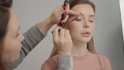 Make-up artist in beauty studio doing makeup for beautiful girl. Woman making Stock Footage 194962149
