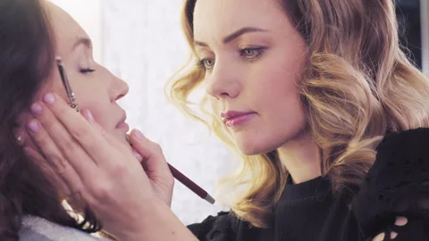 Make-up artist in beauty studio doing makeup for beautiful girl. Stock Footage 303047541