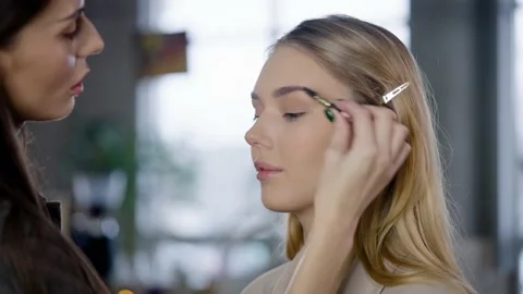 Make-up artist combs and styles the eyebrows of a young blonde woman. Eyebrow Stock Footage 235659557