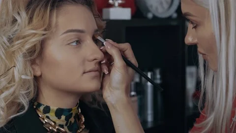 The make-up artist corrects the model's eyebrows with a thin brush and then Stock Footage 157457298