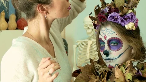 Make-up artist decorating a model with dry flowers after applying Halloween face Stock Footage 82720259