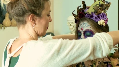 Make-up artist decorating a model with dry flowers after applying Halloween face 库存影片 82720260
