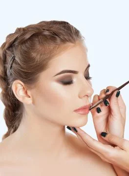 Make-up artist does lips make-up to a woman with smoky eyes makeup. Beautiful Stock Photos
