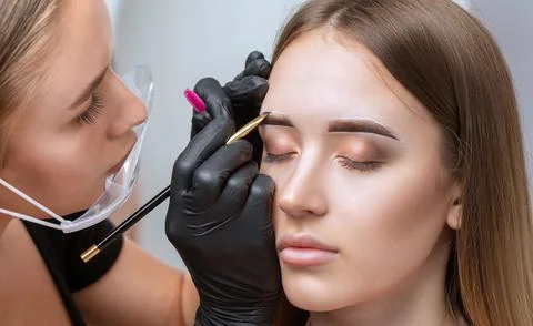 The make-up artist does Long-lasting styling of the eyebrows of the eyebrows  Stock Photos