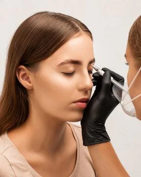 The make-up artist does Long-lasting styling of the eyebrows and will color.. Stock Photos