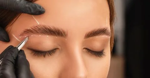 The make-up artist does Long-lasting styling of the eyebrows and will color.. Stock Photos