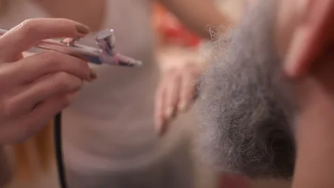 Make-up artist does makeup to a man with a gray beard. Stock Footage 95653184