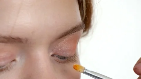 Make-up artist doing make-up of a beautiful young model girl, applies eyeshadow Stock Footage 73938859