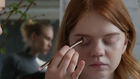 Make-up artist doing make-up of a beautiful young model redhead girl Stock Footage 73939076
