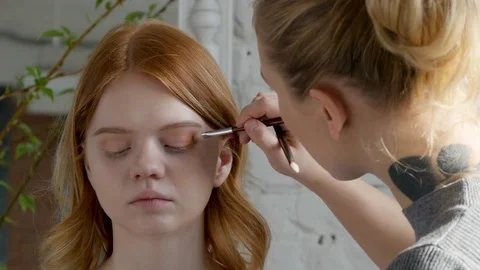Make-up artist doing make-up of a beautiful young model girl, applies eyeshadow, Stock Footage 73939232