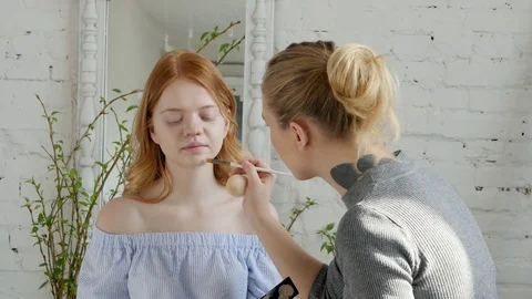 Make-up artist doing make-up of a beautiful young redhead girl, apply concealer  Stock Footage 73939562