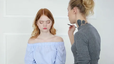 Make-up artist doing make-up of beautiful young redhead girl, applies eyeshadow Stock Footage 73939891