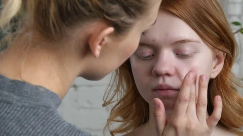 Make-up artist doing make-up of a beautiful young redhead girl, applies cream Stock Footage 73940154