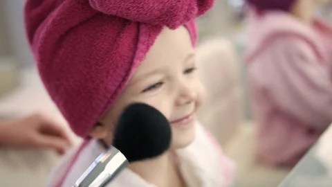 Make up artist doing make up with big brush to pretty little girl in salon Stock Footage 73908439