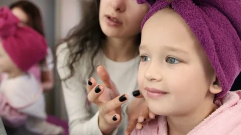 Make up artist doing make up with brush to smiling little girl with towel on her Stock Footage 73908359