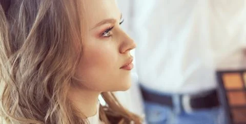 Make-up artist doing make up for young beautiful bride applying wedding make-up Stock Photos