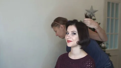 Make-up artist doing makeup and hair styling to a beautiful young woman Video stock 82636862