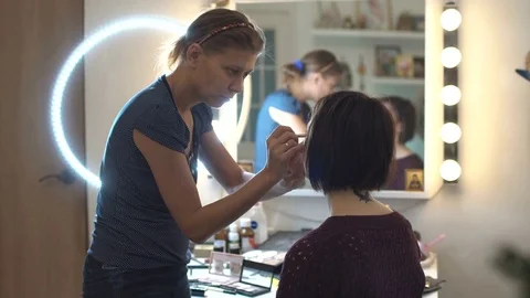 Make-up artist doing makeup and hair styling to a beautiful young woman Stock Footage 82639291