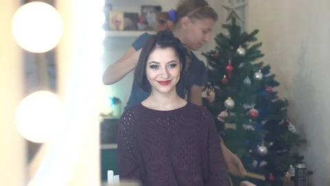 Make-up artist doing makeup and hair styling to a beautiful young woman Stock Footage 82640378