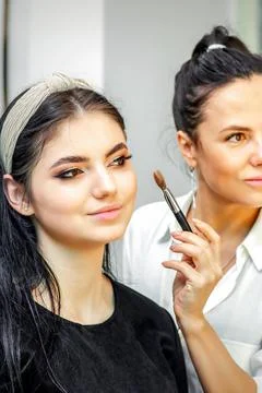 Make-up artist doing makeup for young beautiful bride applying wedding makeup in Stock Photos