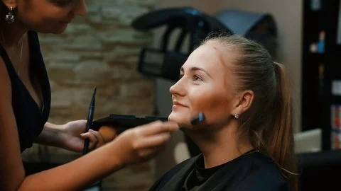 Make up artist doing professional make up of young woman. Stock Footage