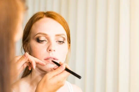 Make up artist doing professional make up of young woman Stock Photos