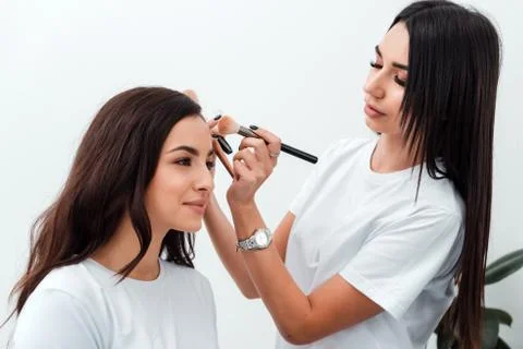 Make up artist doing professional make up of young woman Stock Photos