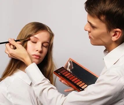 Make up artist doing professional make up of young woman Stock Photos