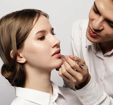Make up artist doing professional make up of young woman Stock Photos
