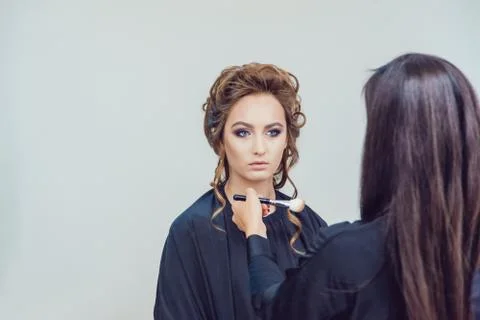 Make up artist doing professional makeup of young woman in beauty studio Stock Photos