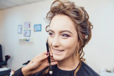 Make up artist doing professional makeup of young woman in beauty studio Stock Photos