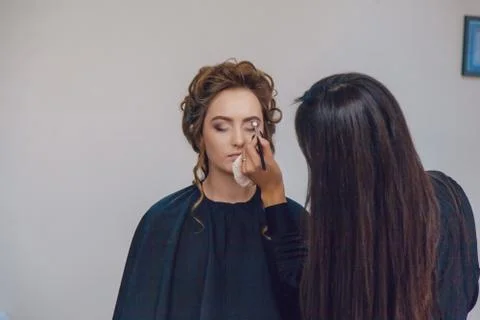 Make up artist doing professional makeup of young woman in beauty studio Foto stock