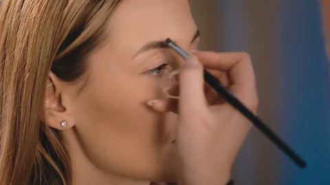 Make-up artist draws and induces the shape of eyebrows with a professional brush Stock Footage 101632815