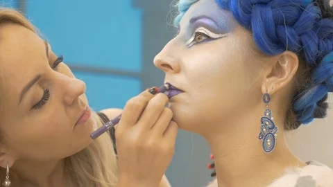 The make-up artist draws the model's lips in purple. Creates a magical image Stock Footage 83842852