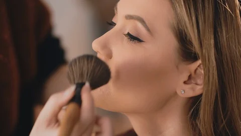 Make-up artist finishes makeup by applying powder with a professional brush on Stock Footage 101235106