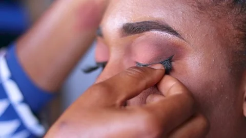 Make up artist Fixing eye lashes on a woman's eye during makeup	 Stock Footage 217875208