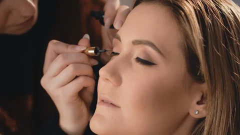 The make-up artist gently puts a black wet eyeliner on the eyelids of the eyes Stock-Footage 101236001