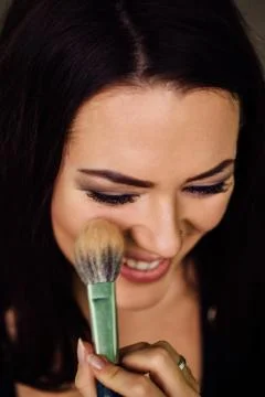 Make-up artist hand applying bright base color on model's face and holding a Stock Photos