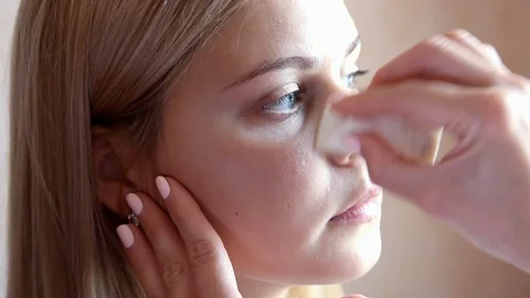 Make-up artist hand wipes model's cheek Stock Footage 103302179