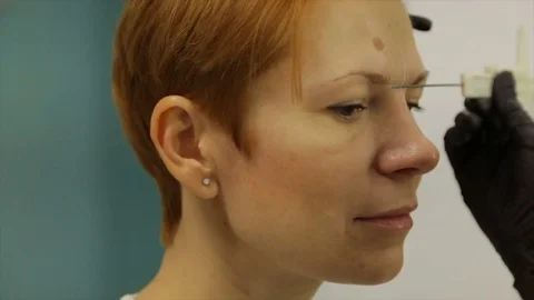 Make-up artist makes eyebrow tattoo for a woman Stock Footage 85321652