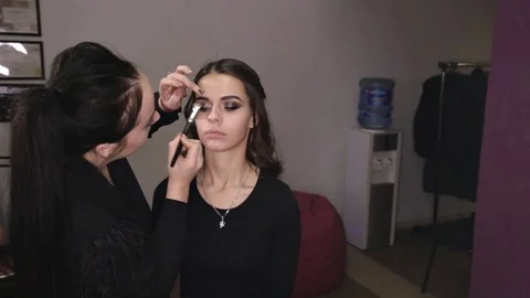 Make-up artist makes make-up an attractive caucasian girl Video stock 84989360