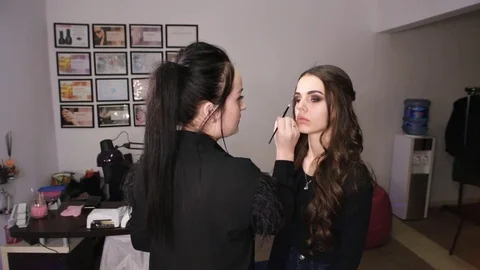 Make-up artist makes make-up an attractive model Stock Footage 84989404