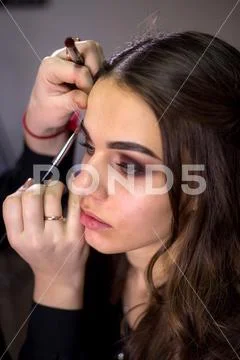 Make-up artist makes make-up an attractive model Stock Photos