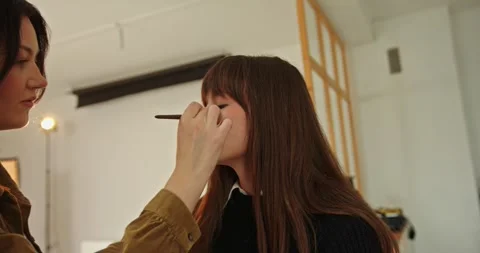 A make-up artist makes a make-up for a beautiful brunette model. Video stock 279913979