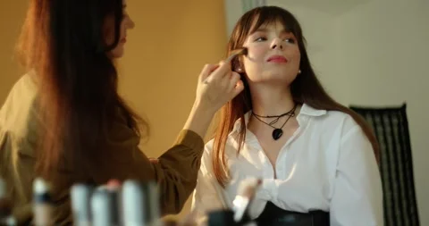 A make-up artist makes a make-up for a beautiful brunette model. Stock Footage 279916130